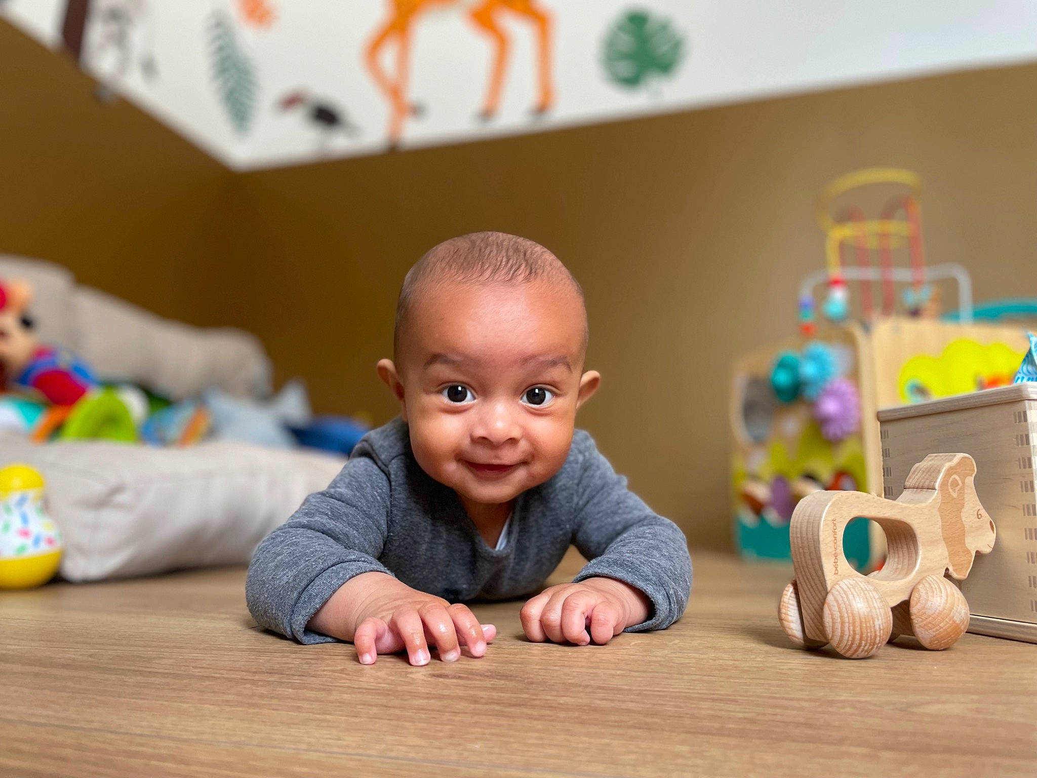 Logan a rejoint le concours — aidez-le/la à gagner de superbes lots ! baby, baby_playing_with_toys, cheek, child, crawling, floor, flooring, fun, happy, hardwood, house, joy, person, room, sitting, skin, smile, thumb, toddler, toy