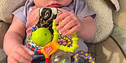 Kinsleigh is registered to the contest to win money with this photo: baby, child, toy, colorful_toy, blue_eyes, clothing, sitting, cushion, blanket, hand, face, indoor, infant, person, play, soft, comfort, cute, expression, young