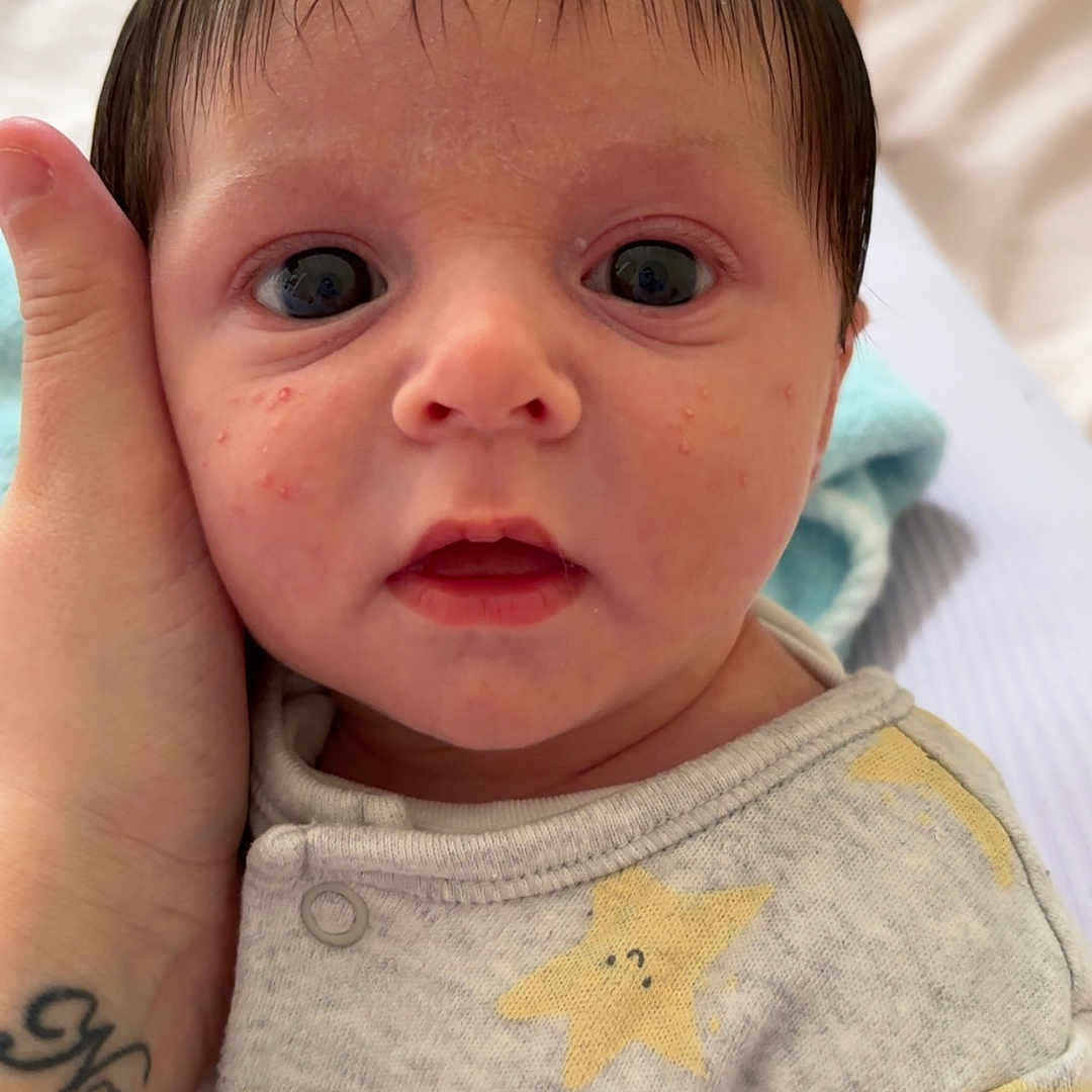 Reuben joined the competition — help win amazing prizes! arm, baby, blanket, bodypart, clothing, couch, ear, face, finger, furniture, hand, head, newborn, person, photography, portrait, skin, t_shirt, tattoo, wrist