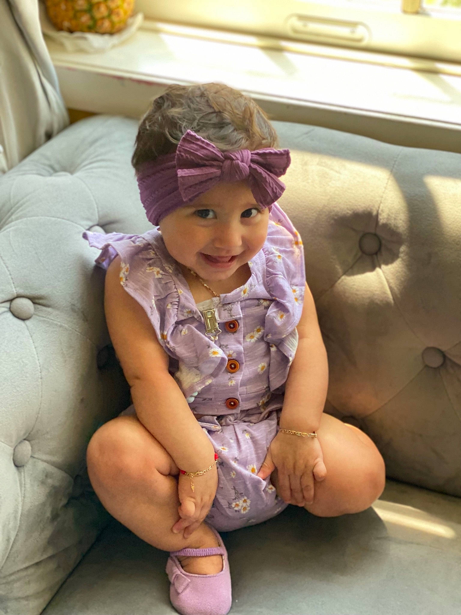Mia is registered to the contest to win money with this photo: baby_toddler_clothing, cap, car_seat, child, comfort, dress, fashion_accessory, foot, fun, happy, hat, headwear, human_leg, joy, knee, person, room, sitting, smile, textile