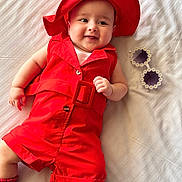 Lamaisah joined the competition — help win amazing prizes! baby, red_clothing, red_hat, smiling, lying_down, bed, white_bedspread, sunglasses, flower_frame, infant, cute, happy, child, indoor, portrait, footwear, sock, fashion, accessories, playful