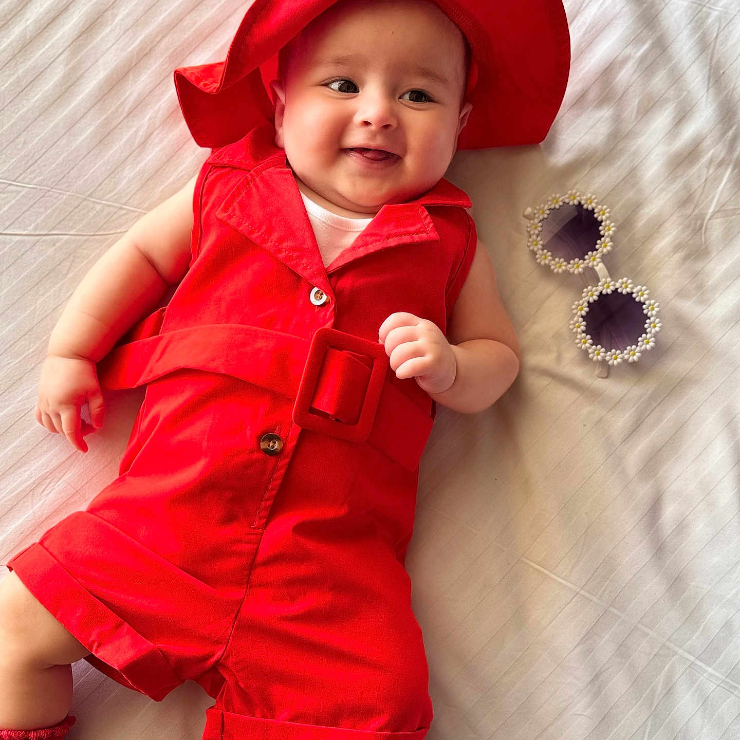 Lamaisah joined the competition — help win amazing prizes! accessories, baby, bed, child, cute, fashion, flower_frame, footwear, happy, indoor, infant, lying_down, playful, portrait, red_clothing, red_hat, smiling, sock, sunglasses, white_bedspread