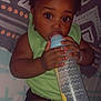 Geneïl a rejoint le concours — aidez-le/la à gagner de superbes lots ! baby, bottle, child, clothing, cute, dark_skin, drinking, expression, face, green_shirt, hand, holding, indoors, infant, lying_down, patterned_blanket, portrait, resting, wide_eyes, young_child