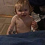 toddler, child, indoor, smiling, curly_hair, shirtless, food_crumbs, fan, denim, floor, door, face, person, messy, happy, candid, young_child, home, baby, playful