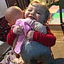 Eva joined the competition — help win amazing prizes! toddler, baby_doll, hugging, child, indoor, playroom, toy, carpet, blanket, plush_toy, colorful, red_clothing, socks, smiling, face, person, floor, furniture, home, cozy