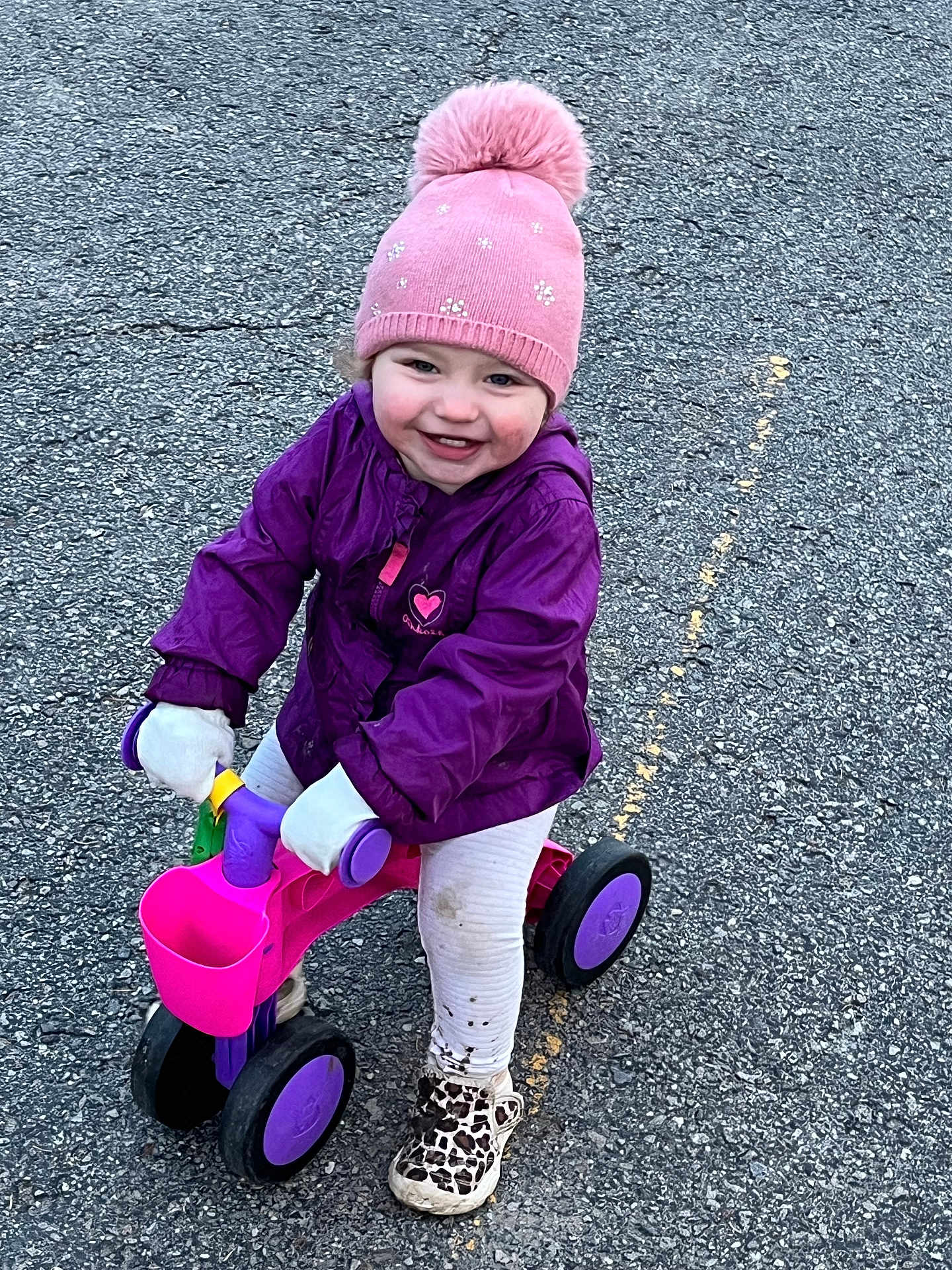 Eva joined the competition — help win amazing prizes! child, toddler, tricycle, pink_hat, purple_jacket, white_leggings, leopard_print_shoes, smiling, outdoor, asphalt, toy, gloves, play, cute, young_child, winter_clothing, small_vehicle, happy, dirt, fun