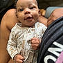baby, infant, child, smiling, face, hand, clothing, pajamas, pattern, animal_print, person, lap, skin, cute, closeup, expression, indoors, comfort, holding, human