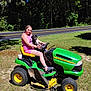 animal, casual_clothing, dog, grass, green, happy, john_deere, lawn_mower, nature, outdoor, pet, recreation, road, smile, summer, sunlight, trees, vehicle, woman, yellow
