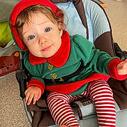 Ambre participe au concours pour gagner de l'argent avec cette photo : toddler, child, baby, elf_costume, striped_leggings, blue_eyes, curly_hair, baby_chair, indoor, carpet, holiday, cute, smiling, red_and_green, festive, seat, foot, hand, face, cozy