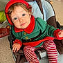 toddler, child, baby, elf_costume, striped_leggings, blue_eyes, curly_hair, baby_chair, indoor, carpet, holiday, cute, smiling, red_and_green, festive, seat, foot, hand, face, cozy