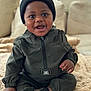 baby, infant, smiling, beanie, hat, jacket, jumpsuit, socks, blanket, couch, sofa, living_room, portrait, cute, happy, big_eyes, dark_skin, hand, feet, plush