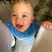 Haroun a rejoint le concours — aidez-le/la à gagner de superbes lots ! toddler, child, happy, smile, drool, blue_shirt, indoor, floor, fabric, hand, eyes, face, person, clothing, texture, joyful, cute, short_hair, skin, playful