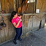 Samira participe au concours pour gagner de l'argent avec cette photo : animal, animal_care, barn, casual_clothing, child, concrete_floor, curly_hair, daylight, farm, footwear, horse, interaction, nature, outdoor, person, pet, rural, stable, wooden_wall, young_girl