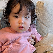 Mei joined the competition — help win amazing prizes! toddler, child, curly_hair, pink_sweater, cozy, couch, indoor, person, hand, face, expression, cute, soft_lighting, seated, clothing, warm, comfortable, portrait, young_child, casual