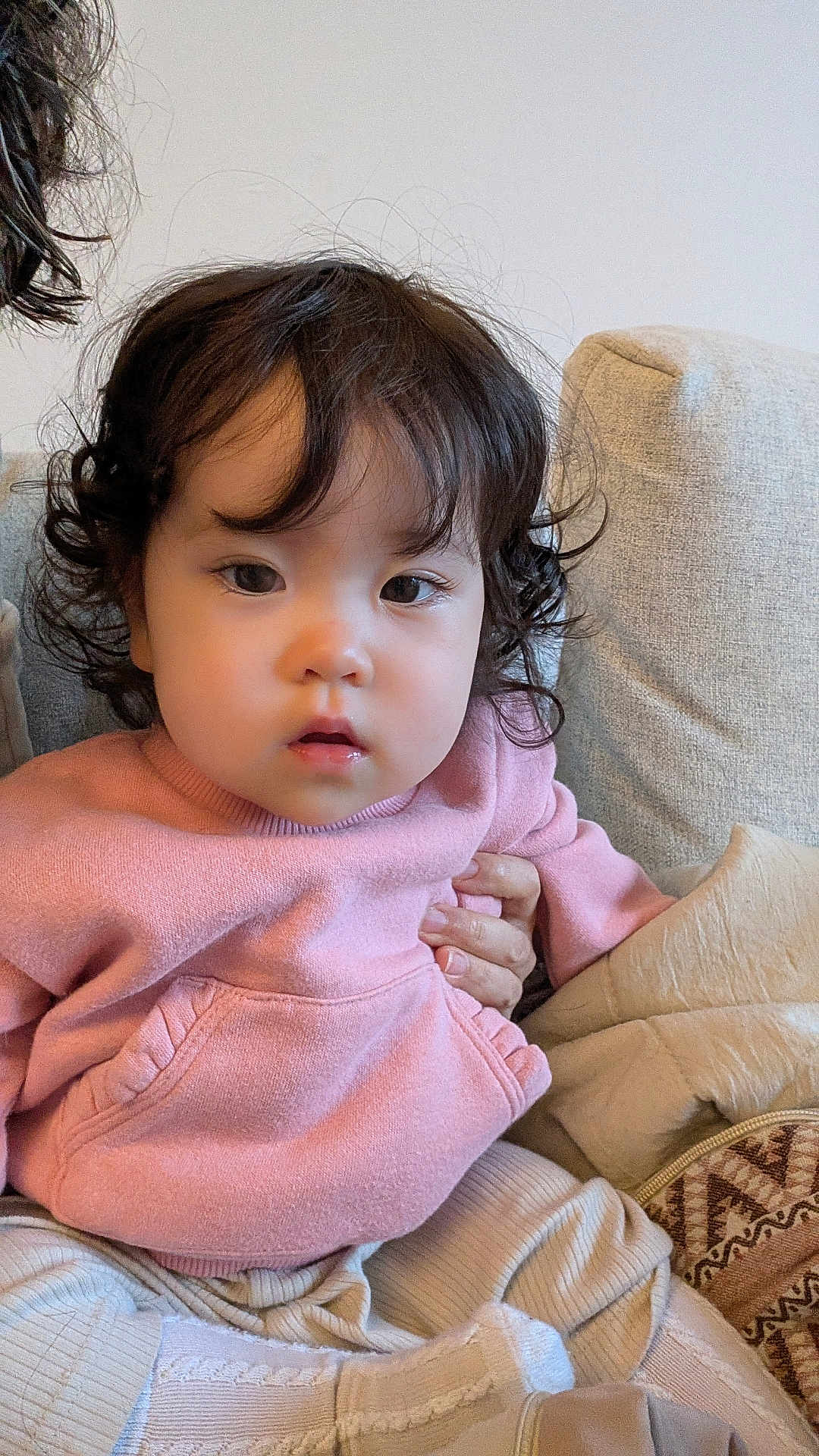 Mei joined the competition — help win amazing prizes! toddler, child, curly_hair, pink_sweater, cozy, couch, indoor, person, hand, face, expression, cute, soft_lighting, seated, clothing, warm, comfortable, portrait, young_child, casual