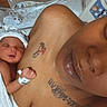 newborn, baby, infant, parent, hospital, hospital_bed, sleeping, face, portrait, family, bonding, blanket, wristband, tattoo, skin_to_skin, indoors, medical_setting, closeup, tender, photograph
