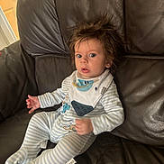 Henry joined the competition — help win amazing prizes! baby, child, infant, striped_onesie, bib, cartoon_duck, wide_eyes, spiky_hair, leather_couch, indoor, person, seated, cute, expression, home, furniture, clothing, young_child, portrait, surprised