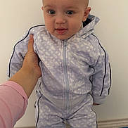 Bastien participe au concours pour gagner de l'argent avec cette photo : baby, child, person, hand, clothing, tracksuit, sneakers, footwear, striped_blanket, indoor, standing, holding, cute, young, casual_wear, wall, floor, human, portrait, expression