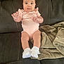 Lily is registered to the contest to win money with this photo: baby, infant, onesie, socks, couch, blanket, indoor, child, person, cute, sitting, clothing, face, head, skin, legs, feet, furniture, young, adorable