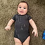 Lily is registered to the contest to win money with this photo: baby, infant, onesie, carpet, floor, cute, child, person, smiling, blue_eyes, patterned_clothing, indoor, skin, hand, leg, foot, happy, lying_down, guitar_pattern, plush