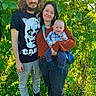 baby, child, family, parents, infant, smiling, portrait, outdoor, garden, foliage, plants, greenery, sunlight, standing, holding, toddler, shirt, clothing, nature, family_portrait