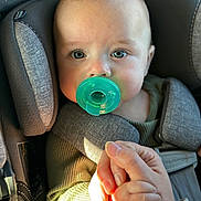 Oliver joined the competition — help win amazing prizes! baby, pacifier, car_seat, child, hand, holding_hand, green, seatbelt, closeup, infant, person, safety, cute, young_child, portrait, sunlight, clothing, adult_hand, bond, secure