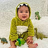 Andy is registered to the contest to win money with this photo: baby, child, dinosaur_costume, green, smiling, toy_dinosaurs, fluffy_blanket, cute, sitting, happy, infant, plush_toy, soft_texture, indoors, portrait, playful, costume, feet, hands, young_child