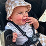 baby, child, smiling, hat, bucket_hat, checkered, stroller, seatbelt, happy, cute, infant, clothing, hand, face, cheeks, fingers, outdoor, daylight, closeup, person
