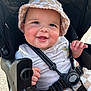baby, smiling, bucket_hat, stroller, child, happy, seatbelt, cute, cheeks, infant, clothing, outdoor, sunlight, person, toddler, young_child, face, expression, safety, casual_wear
