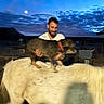 animal, blue_sky, brown_animal, cattle, clouds, collar, cow, dog, farm, livestock, man, moon, motion_blur, night, outdoors, pet, riding, rural, sunset, white_cow