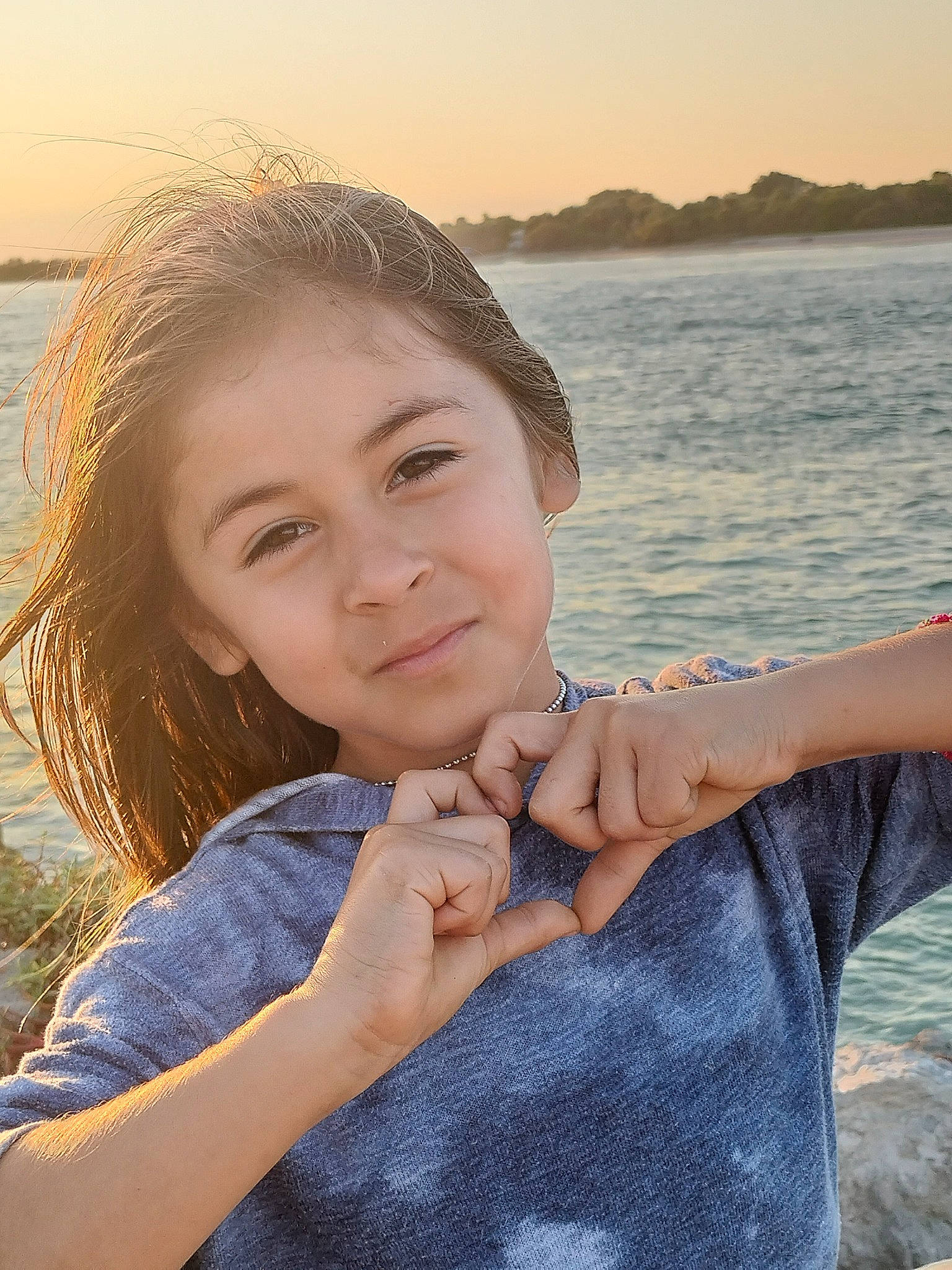 Aliana is registered to the contest to win money with this photo: arm, eye, face, finger, flash_photography, fun, gesture, hand, happy, horizon, joy, lake, leisure, lip, pattern, people_in_nature, person, sitting, sky, smile