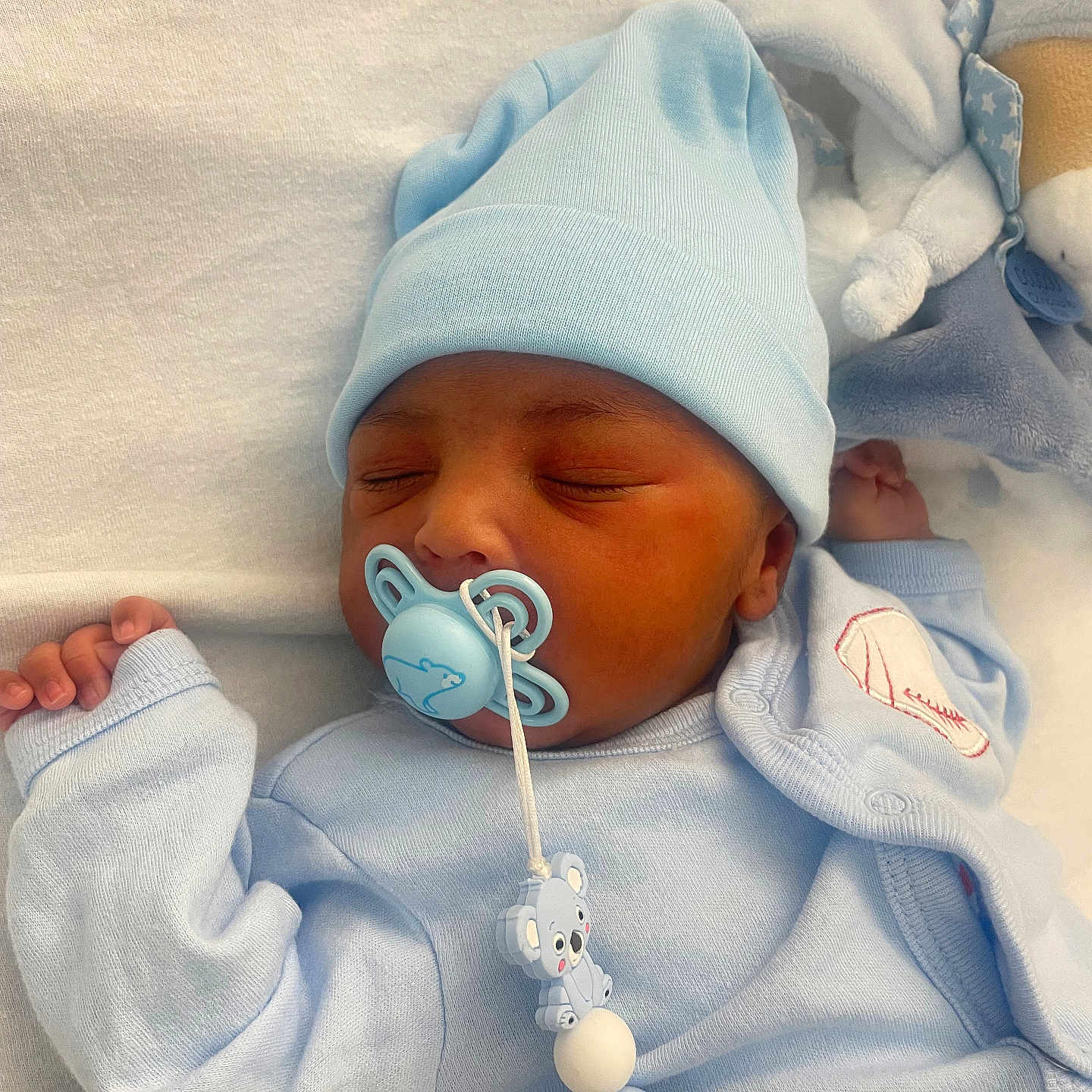 Jayden a rejoint le concours — aidez-le/la à gagner de superbes lots ! baby, bed, blanket, blue_clothing, child, closeup, comfort, cute, face, hand, hat, indoors, infant, newborn, pacifier, peaceful, rest, sleeping, soft_toy, toddler
