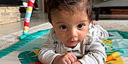 Uday joined the competition — help win amazing prizes! baby, child, play_mat, indoor, floor, carpet, curious, infant, hands, face, person, living_room, couch, blanket, toys, colorful, closeup, portrait, casual, home