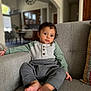 Uday is registered to the contest to win money with this photo: baby, child, infant, couch, sofa, indoor, clothing, sweater, pants, barefoot, face, eyes, hair, person, home, living_room, furniture, curious, seated, portrait