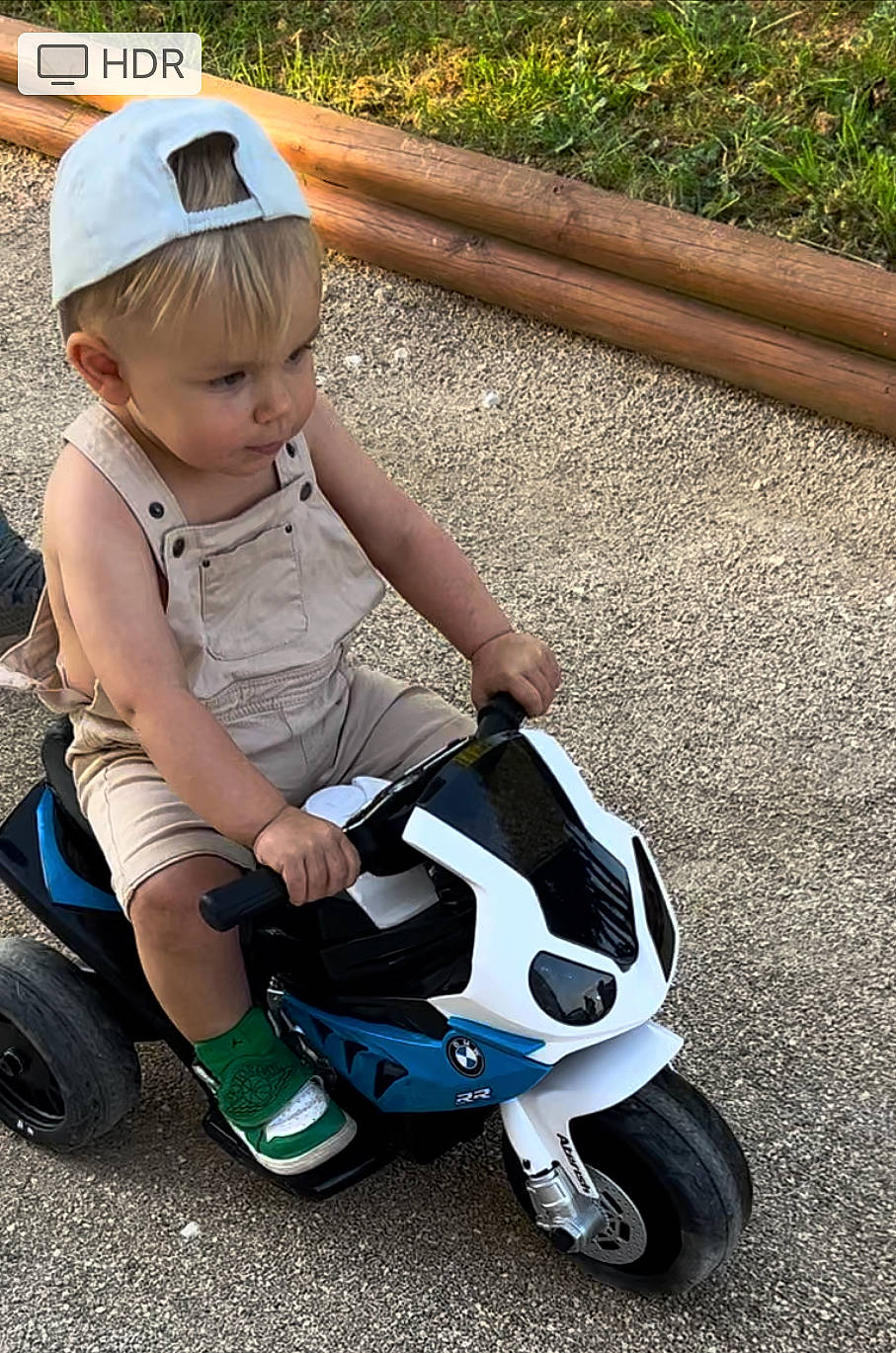 Mayron participe au concours pour gagner de l'argent avec cette photo : automotive_design, automotive_lighting, automotive_tire, automotive_wheel_system, baby_toddler_clothing, baseball_cap, cap, fun, grass, helmet, motor_vehicle, person, riding_toy, rolling, shoe, sneakers, tire, toddler, toy, vehicle