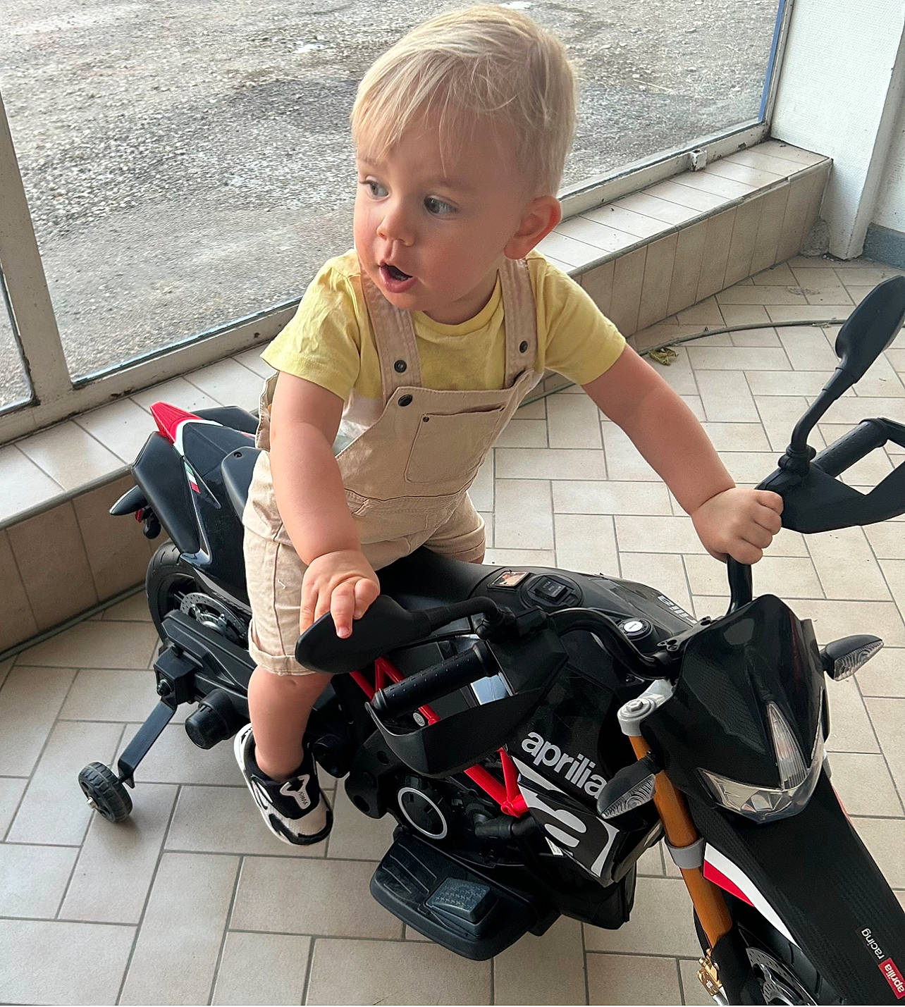 Mayron a rejoint le concours — aidez-le/la à gagner de superbes lots ! automotive_tire, baby, baby_carriage, baby_products, baby_toddler_clothing, bag, child, flooring, joint, knee, leg, luggage_and_bags, person, personal_protective_equipment, product, reflex_camera, shoe, sitting, sneakers, surprise