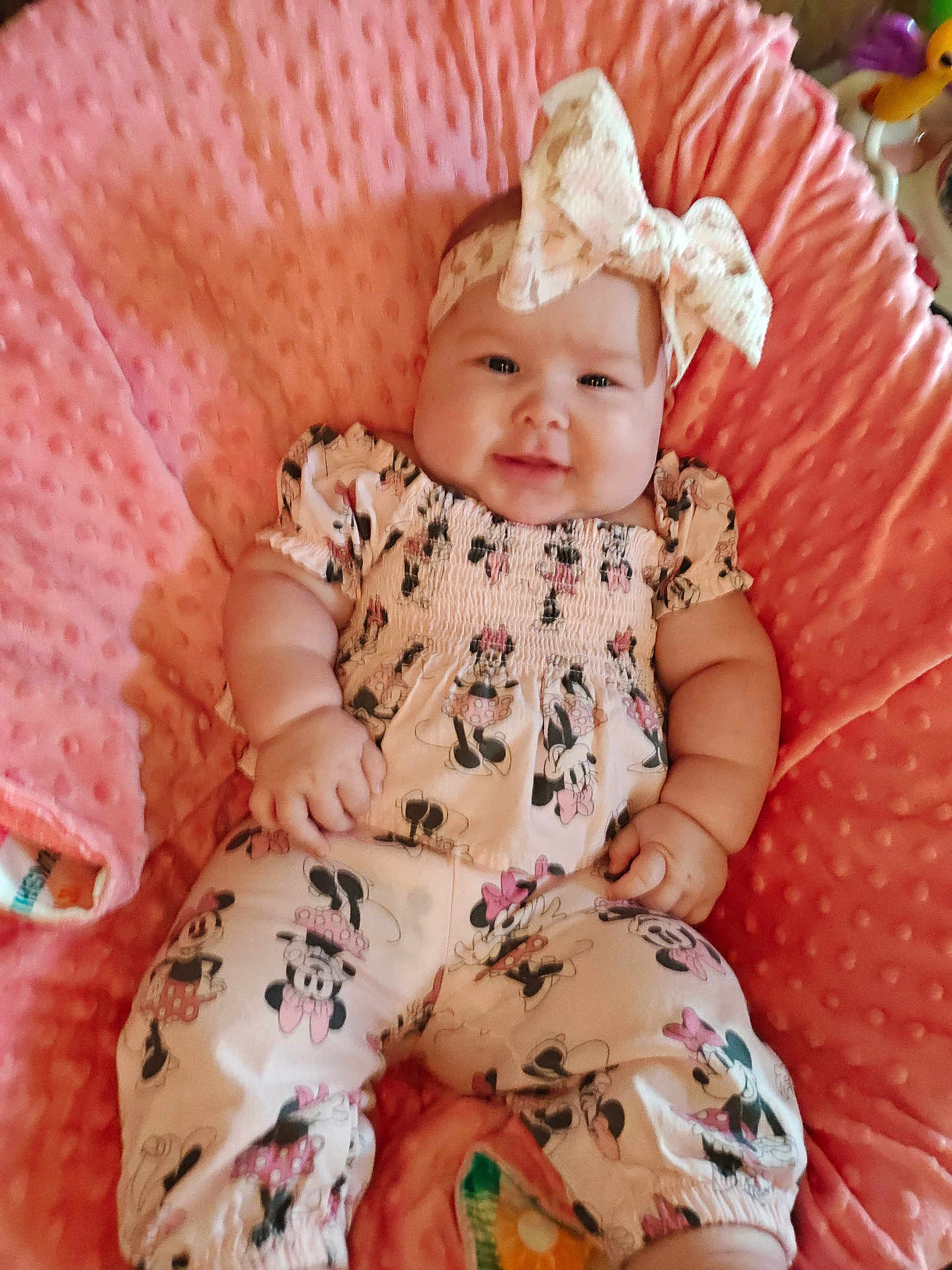 Parker is registered to the contest to win money with this photo: baby, child, smiling, pink_blanket, headband, bow, minnie_mouse, clothing, cute, portrait, infant, soft_texture, happy, lying_down, chubby_cheeks, indoors, plush, person, toddler, fashion