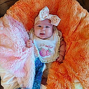Parker joined the competition — help win amazing prizes! baby, infant, headband, bib, blanket, orange, pink, blue, soft_texture, cute, chubby_cheeks, smiling, portrait, cozy, indoors, child, person, clothing, sleepwear, comfort