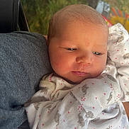 Hope is registered to the contest to win money with this photo: newborn, baby, infant, child, face, portrait, sleepy, awake, side_eye, cuddled, onesie, clothing, patterned, pink, gray, adult, outdoor, sunlight, greenery, closeup