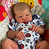 baby, infant, child, portrait, lying_down, spiderman, onesie, colorful, blanket, play_mat, face, hands, legs, eyes, indoors, close_up, patterned, textile, happy, adorable