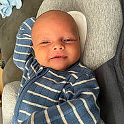 Hudson is registered to the contest to win money with this photo: baby, infant, face, smile, blue_clothing, striped_clothing, onesie, cushion, gray_cushion, relaxing, portrait, indoor, child, young, human, comfort, soft, resting, cute, happy
