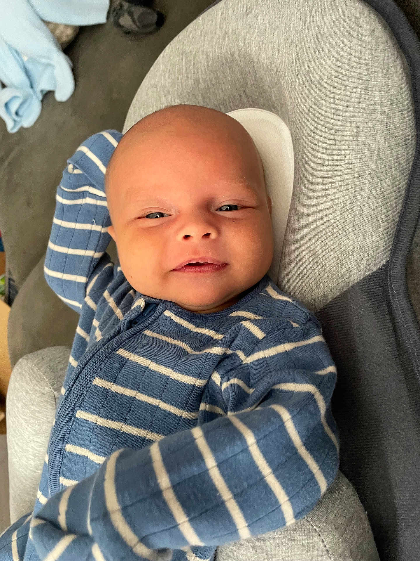 Hudson is registered to the contest to win money with this photo: baby, infant, face, smile, blue_clothing, striped_clothing, onesie, cushion, gray_cushion, relaxing, portrait, indoor, child, young, human, comfort, soft, resting, cute, happy