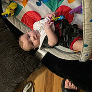 Phoenix is registered to the contest to win money with this photo: baby, child, clothing, colorful, curious, cushion, face, floor, footwear, holding, indoor, infant, person, pikachu, play_mat, plush_toy, relaxing, sock, toy, wood_floor