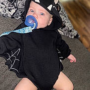 Phoenix is registered to the contest to win money with this photo: baby, bat, black_clothing, blanket, blue_eyes, child, comfort, costume, couch, cute, fabric, face, hood, indoor, infant, legs, pacifier, relaxed, soft_toys, web_wings