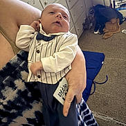 Wyatt is registered to the contest to win money with this photo: baby, infant, child, person, clothing, tuxedo, bowtie, hand, carpet, drawer, room, furniture, fabric, holding, indoor, portrait, newborn, adult, cozy, casual