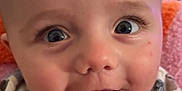 John Lee joined the competition — help win amazing prizes! baby, close_up, smiling, face, infant, onesie, patterned_clothing, happy, eyes, mouth, skin, head, blanket, indoor, child, cute, expression, portrait, young, cozy