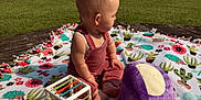 Stormi joined the competition — help win amazing prizes! baby, blanket, cactus_pattern, child, clothing, colorful, cube_toy, cute, daytime, flower_pattern, grass, greenery, infant, nature, outdoor, playtime, plush, sitting, sunlight, toy