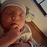 Dallas is registered to the contest to win money with this photo: newborn, baby, sleeping, infant, portrait, close_up, face, hand, fist, hat, onesie, blanket, bed, indoor, cozy, peaceful, child, babywear, soft_lighting, resting