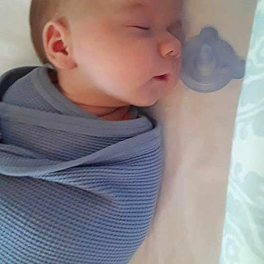Adonis is registered to the contest to win money with this photo: arm, baby, baby_products, baby_sleeping, baby_toddler_clothing, cheek, child, comfort, electric_blue, linens, mouth, neck, nose, pattern, room, sitting, skin, sleeve, t_shirt, toddler