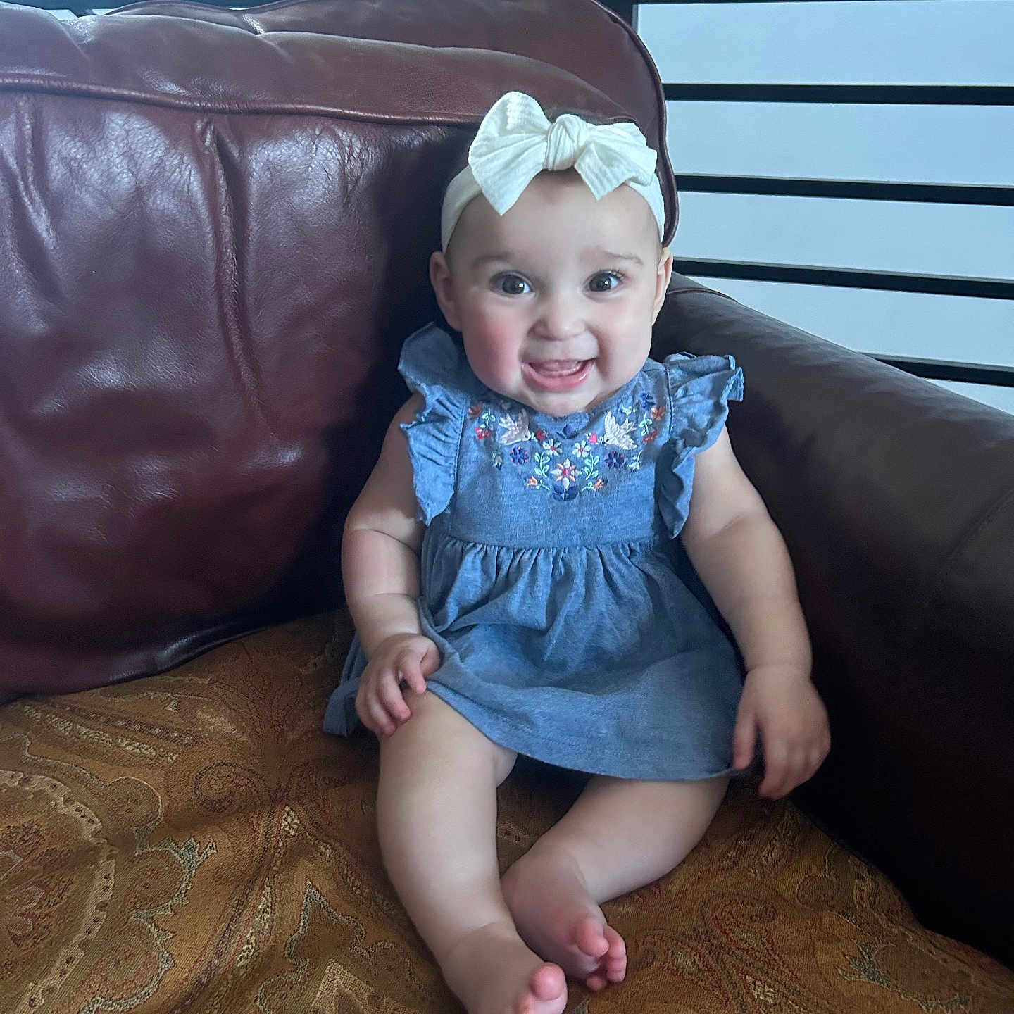 Eliana is registered to the contest to win money with this photo: baby, bonnet, cap, chair, clothing, couch, cushion, dress, face, furniture, happy, hat, head, homedecor, indoors, pants, person, photography, portrait, sitting